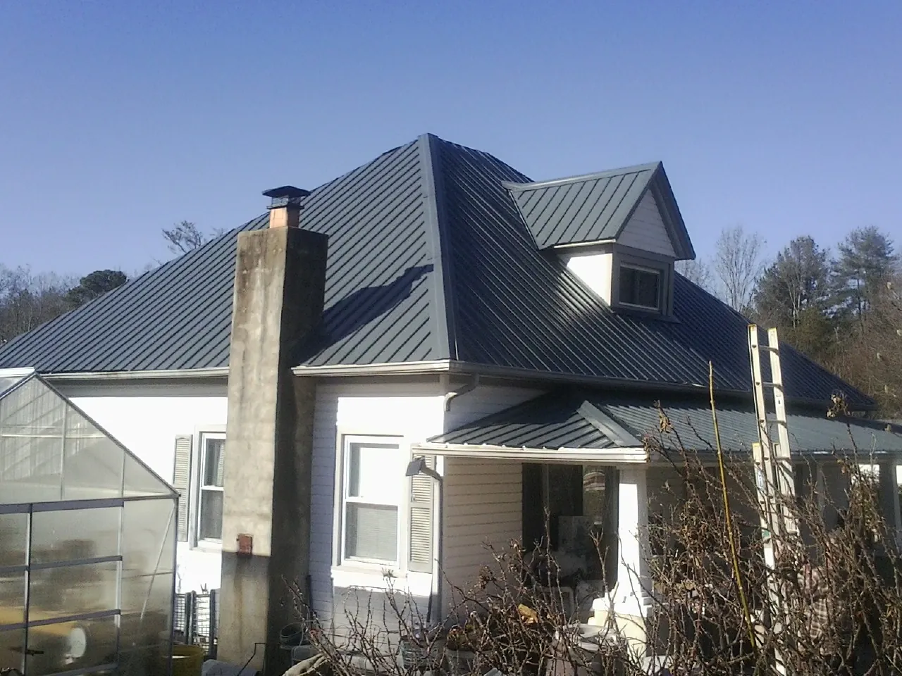 Dark blue standing seam metal roof on a white farmhouse with dormer — Slate & Tile Roof Repair by Roofing Brothers in York Haven