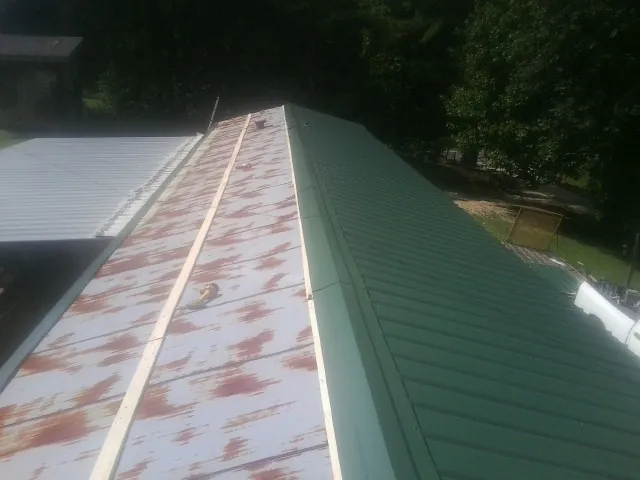 Old rusted panels beside newly installed green metal roofing — Wind Damage Roof Repair by Roofing Brothers in York Haven