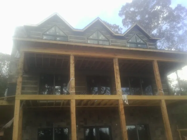 Dormers and porch framing on a large log home under construction — Roof Coating work by our crew in York Haven