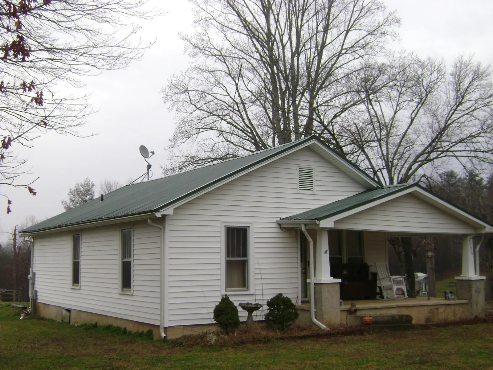 Green metal roof on a white bungalow with a side porch in York Haven