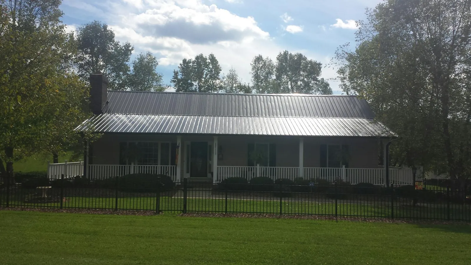 Gray metal roof on a brick ranch with a full width front porch — Gutter Guard Installation work by our crew in York Haven