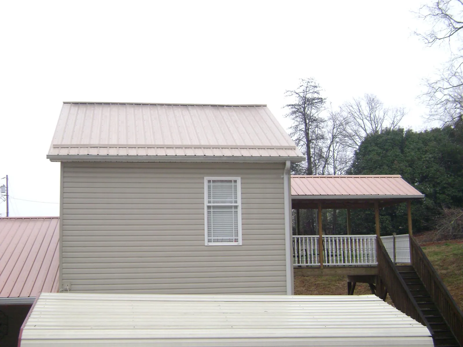 Tan metal roofs on a two story addition and attached porch, from a Roof Replacement job in York Haven