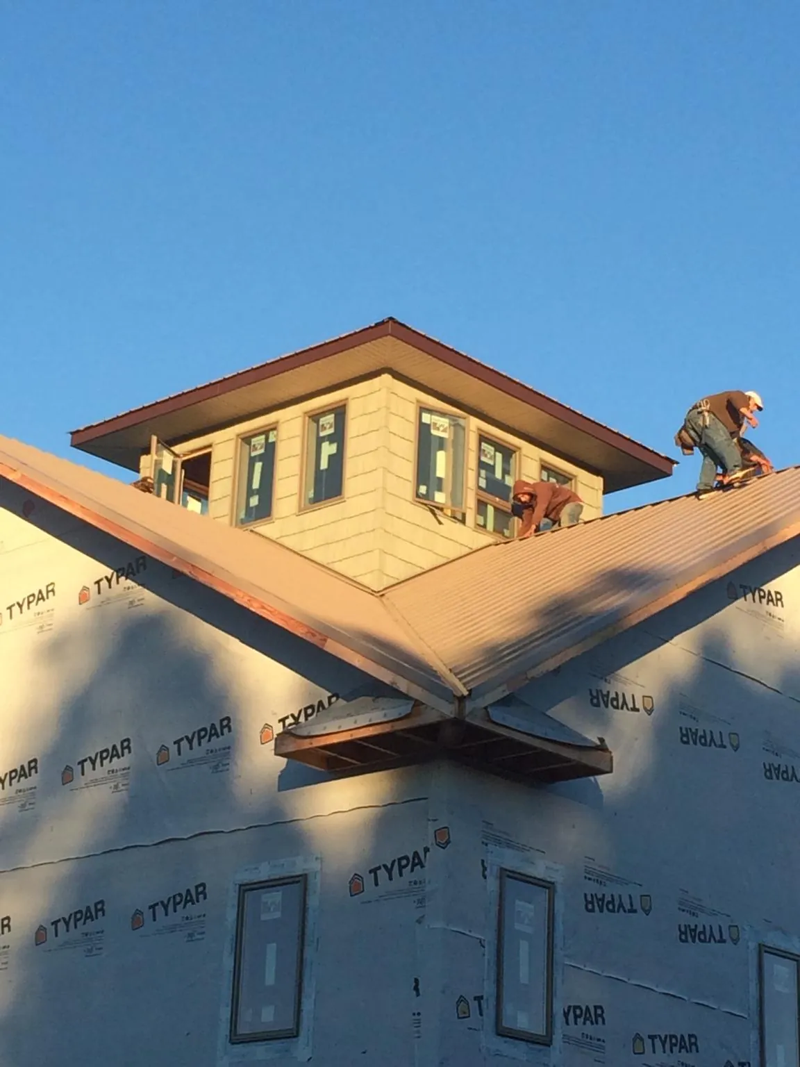 Roofers working around a rooftop cupola on a new metal roof at sunset — Roof Waterproofing in York Haven by Roofing Brothers